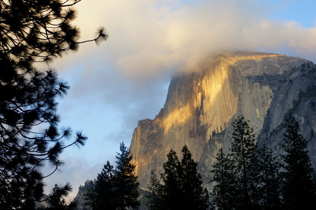 Clouds form around Half Dome at sunset.